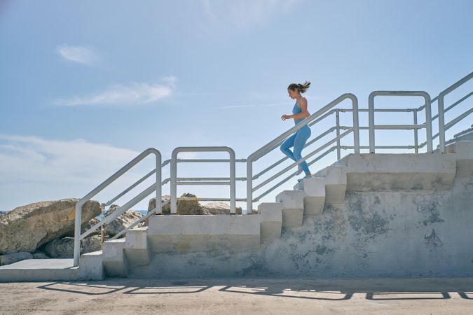 Runner jogging on staircase during workout in sunlight