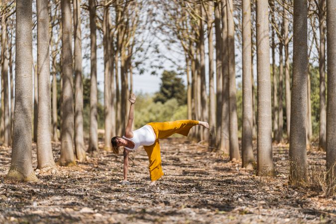 Adult expectant mother practicing yoga in park during sunny day