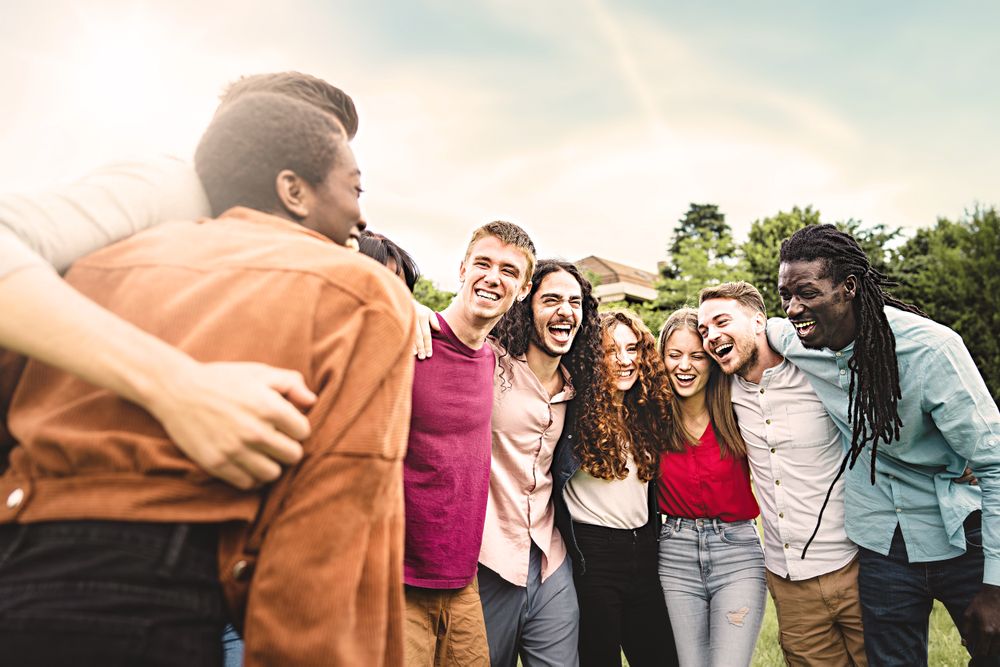 Multiethnic group of joyful young people laughing and interacting together in the park