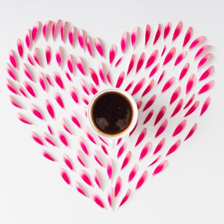 Heart made of pink flower petals with coffee