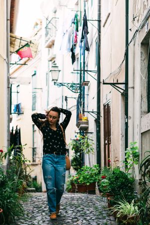 Young casual brunette walking on cobblestone street of old city