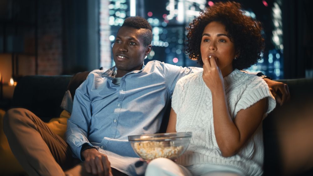 Black Woman Watches New Movie and Eating Popcorn at Home in Stylish Loft Apartment.