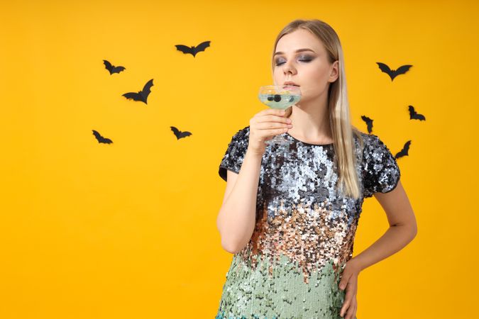 A woman at a party in the style of Halloween with a cocktail in her hands