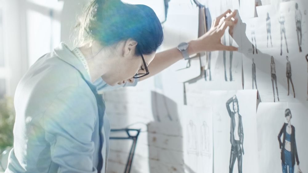 Female fashion, designer,  Choosing Sketches for Her Project and Pinning them to the Wall.