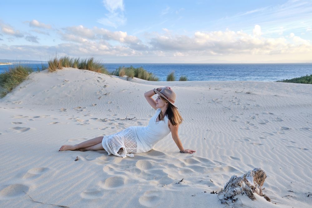 Woman in white dress relaxing on sand