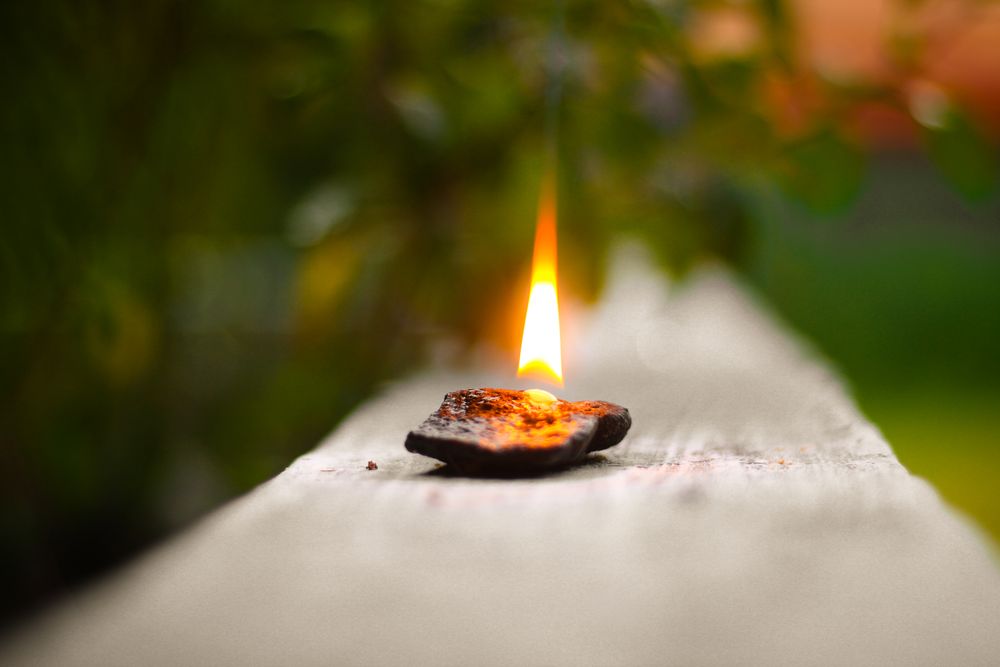 Lit diya on gray concrete pavement