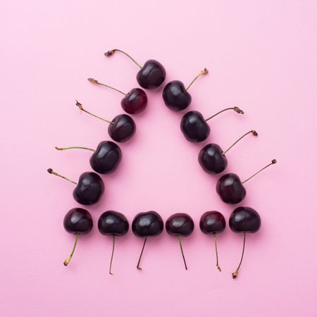Cherries in a triangle shape on pink background