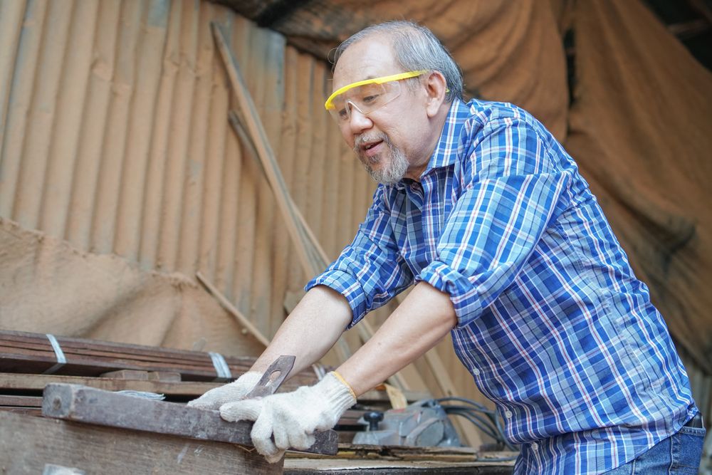 Asian male woodworker with a wooden panel in the shop