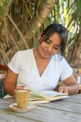 Smiling young woman reading book in outdoor cafe