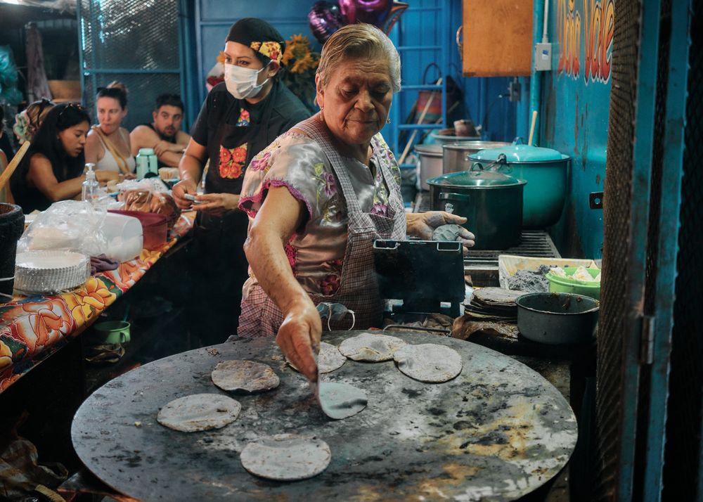 Woman putting fresh tortillas on outdoor grill