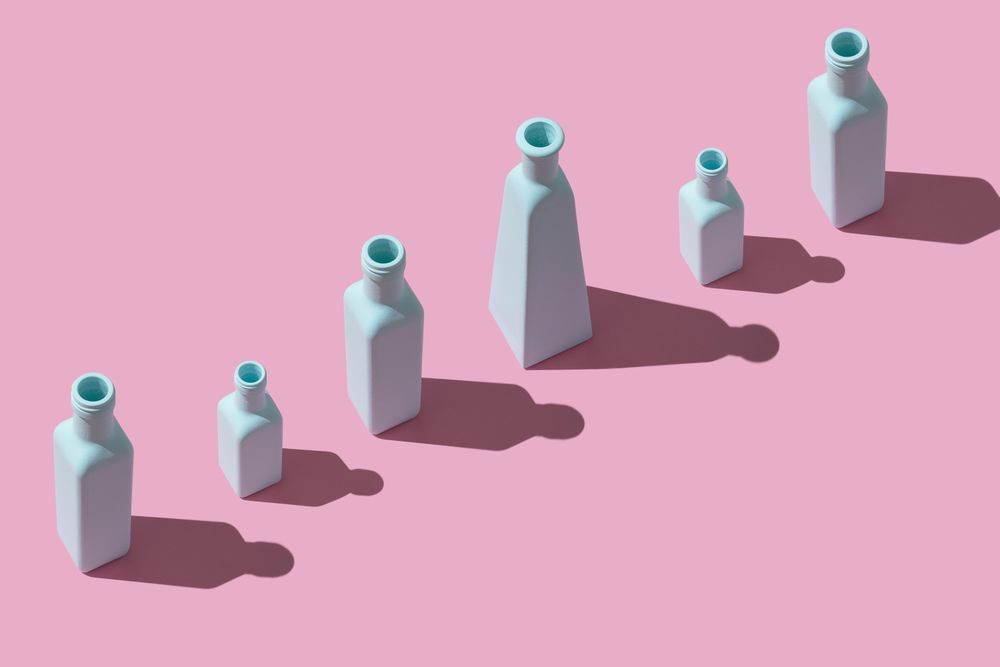 Single row of painted glass bottles on pink background