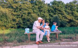 Older man feeding baby girl sitting in a bench 4B1wk5