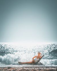 Woman in swimsuit laying on lounge chair on sea wave 4A89N5