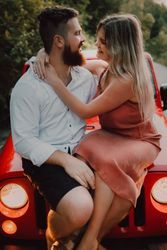 Loving couple sitting on car on road near forest