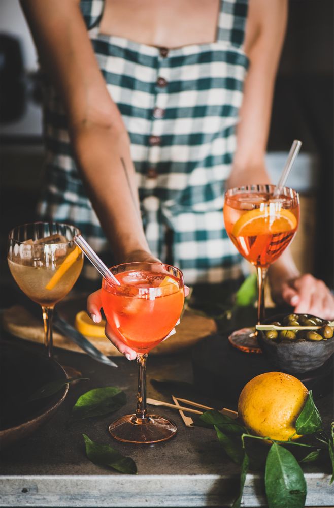 Young woman in checkered dress holding aperitif with orange slices