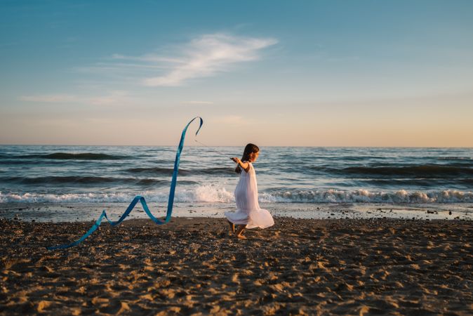 Adorable girl playing with ribbon on seaside
