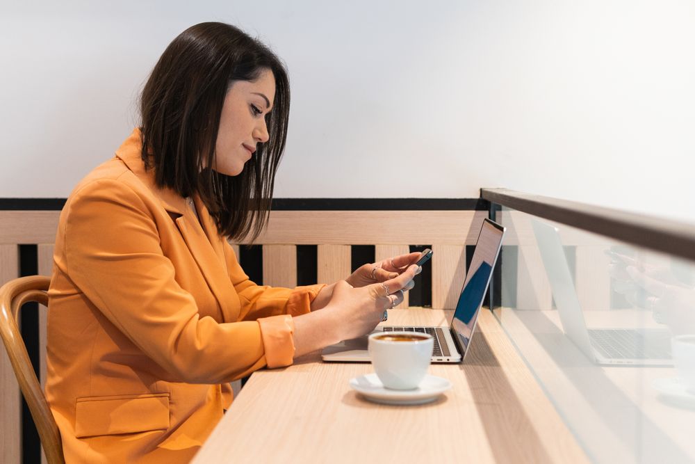 Woman using smartphone and working in cafe