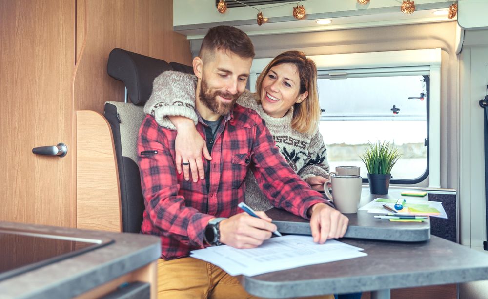 Male and female couple smiling while working in back of van
