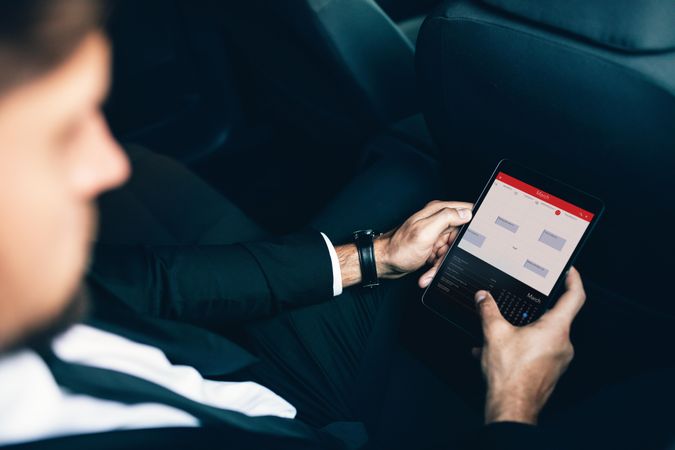 Business executive traveling by car and using tablet