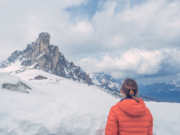 Woman in warm jacket looking at snowy mountain landscape