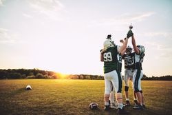 Men holding up a trophy and celebrating winning a football game