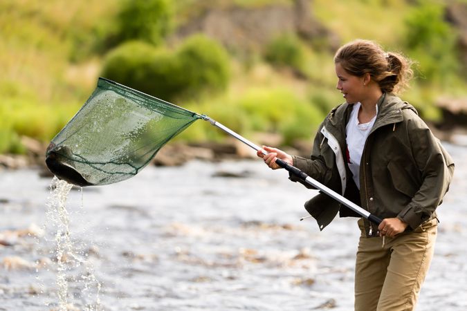 Female Fisherman Lifting Net from River