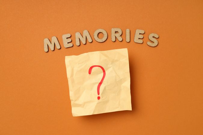 The word “Memories” written in cork on dusty orange background with post it note