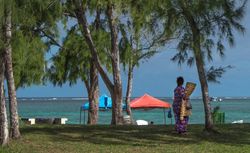Older woman walking along ocean front with blanket for picnic