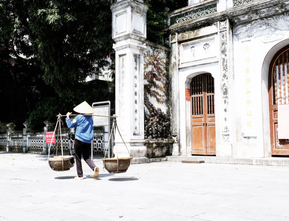 Asian farmer with conical hat holding a shoulder yoke