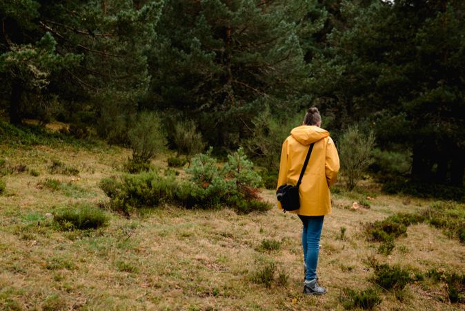 Person in yellow raincoat walking i forest