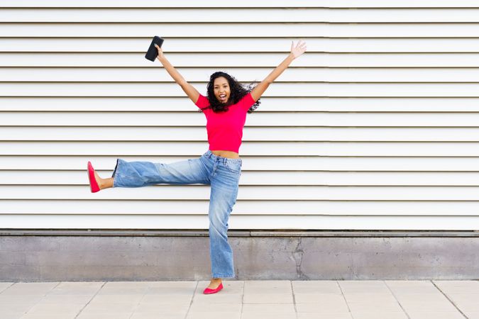 A Joyful Young Woman Celebrating Excitedly Outdoors While Wearing a Stylish and Trendy Outfit