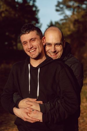 Smiling men hugging on path in park