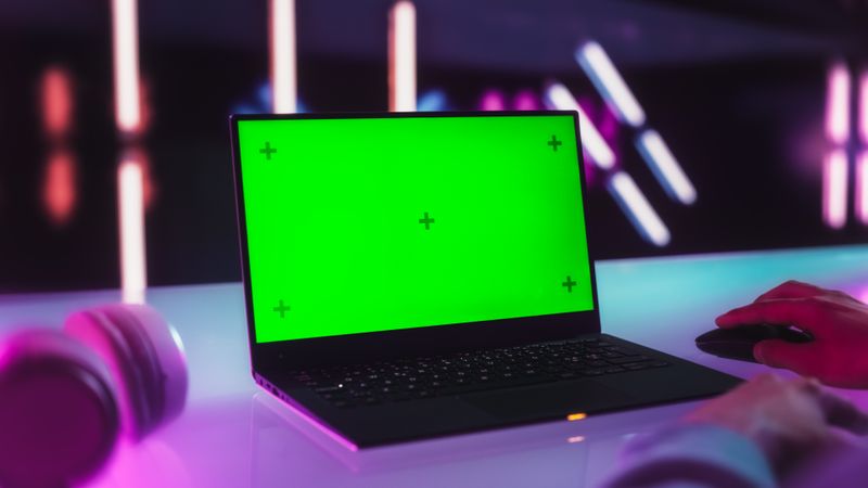 Anonymous Content Creator Using a Laptop Computer with Mock Up Green Screen Chromakey Display with Motion Tracker Placeholders. Photo Template for Gamers, Computer Products and Software