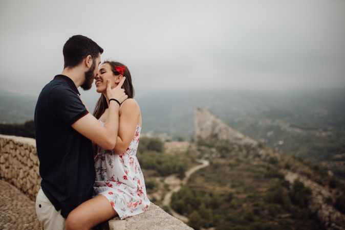 Sensual couple kissing while resting on rural observation desk