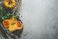 Healthy seasonal food background with pumpkins, fresh herbs and cutlery  on rustic background, top view. Border