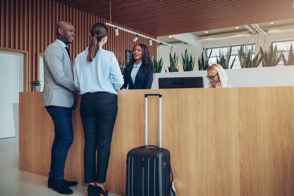 Two guests arrive with luggage at the front desk