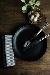 Top view of dark plates for Easter dinner with decorative nest