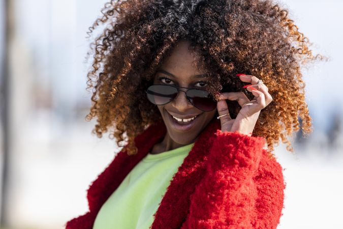 Happy female with hand to her sunglasses on sunny day