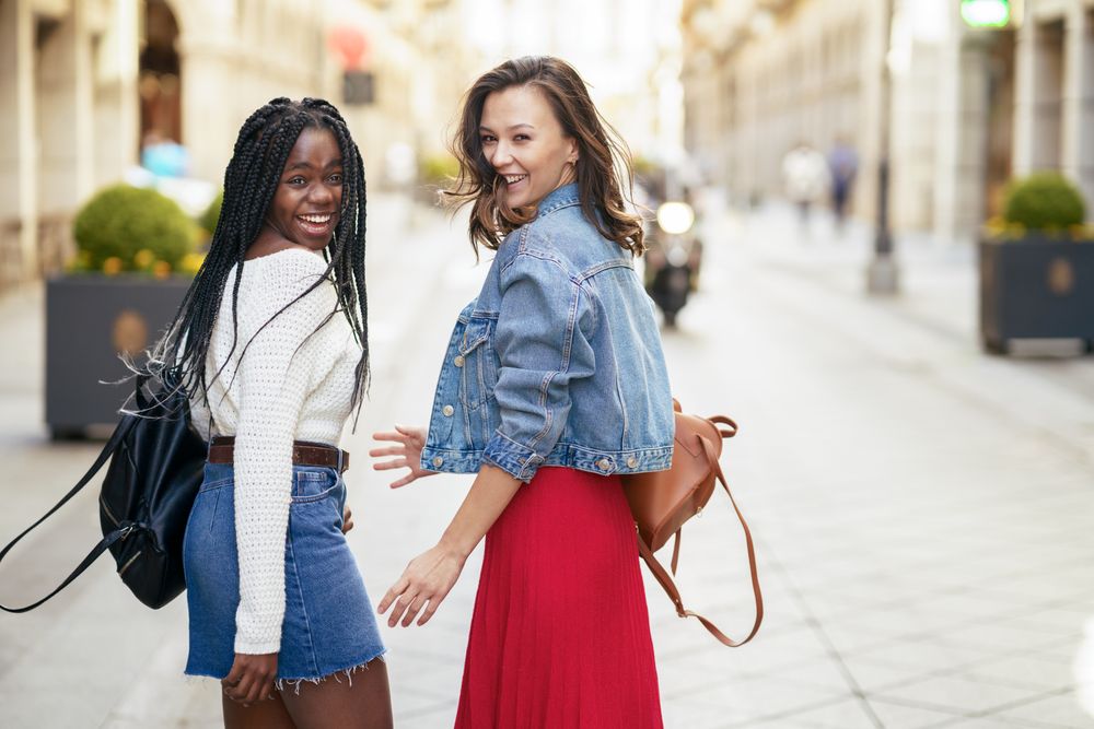 Female friends walking on an outdoor street while looking back