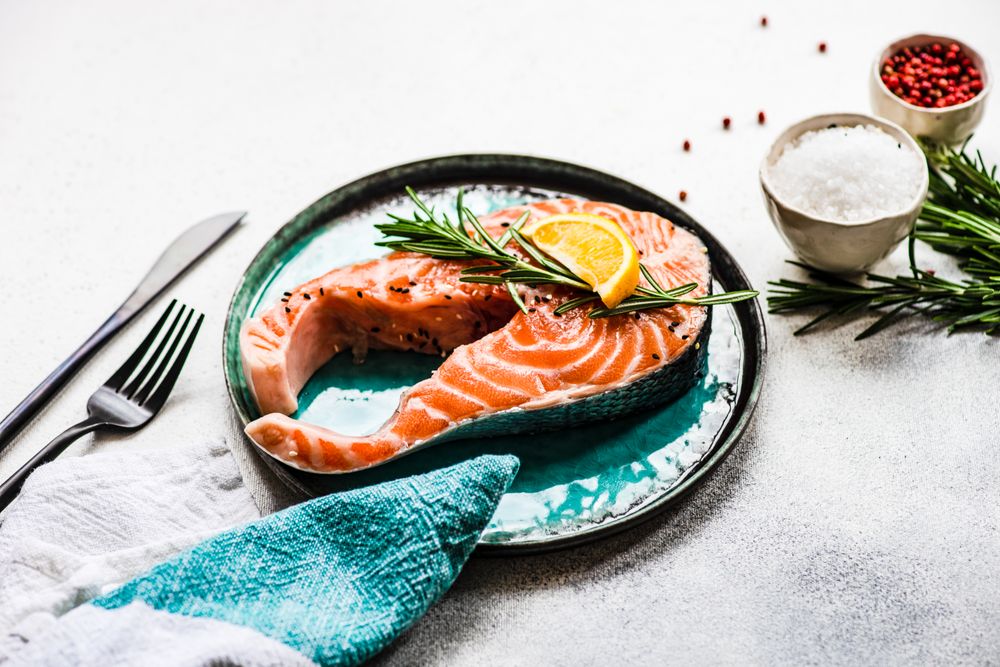 Salmon fish with rosemary and lemon on stone background with copy space