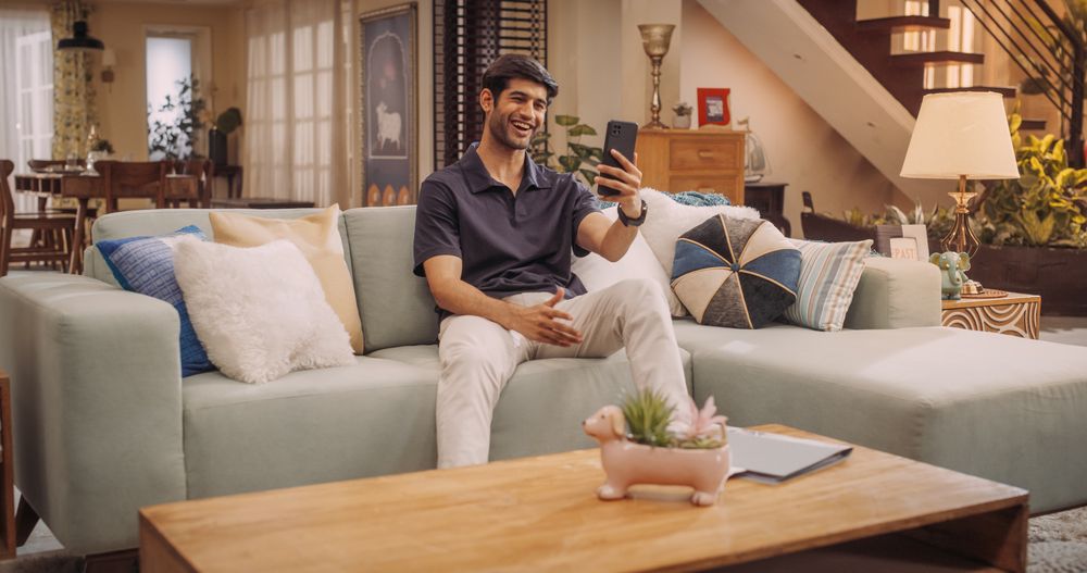 Indian Man Using Smartphone while on Video Call at Home, Doing Remote Work