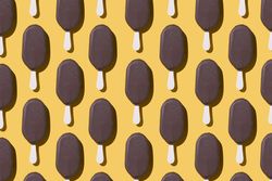 Chocolate popsicle lined up in neat order on a yellow background