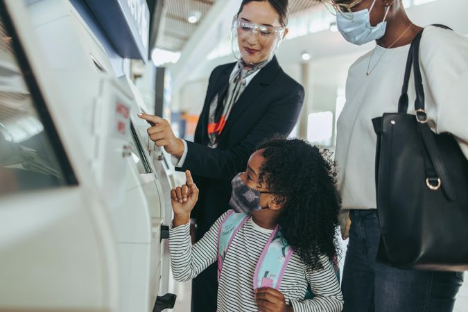 Airport attendant helping  family of two doing self check-in