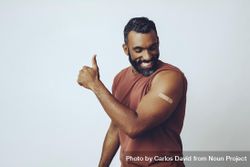 Proud man flexing arm with vaccination and giving thumbs up, copy space 43Wqr4