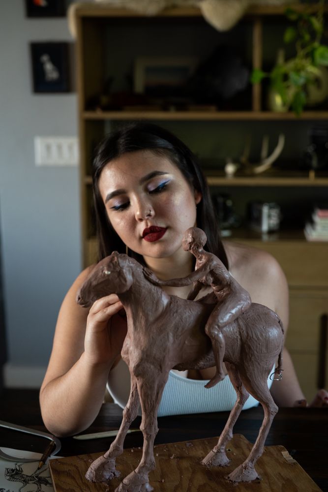 Young woman working on clay sculpture inside at work table