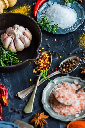 Pink Himalayan salt, and spices on dark counter with copy space