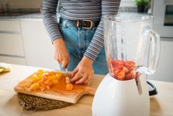 Crop woman cutting fruits for smoothie