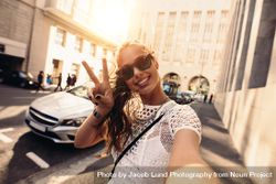 Happy woman smiling at camera and showing peace sign 0yyG70