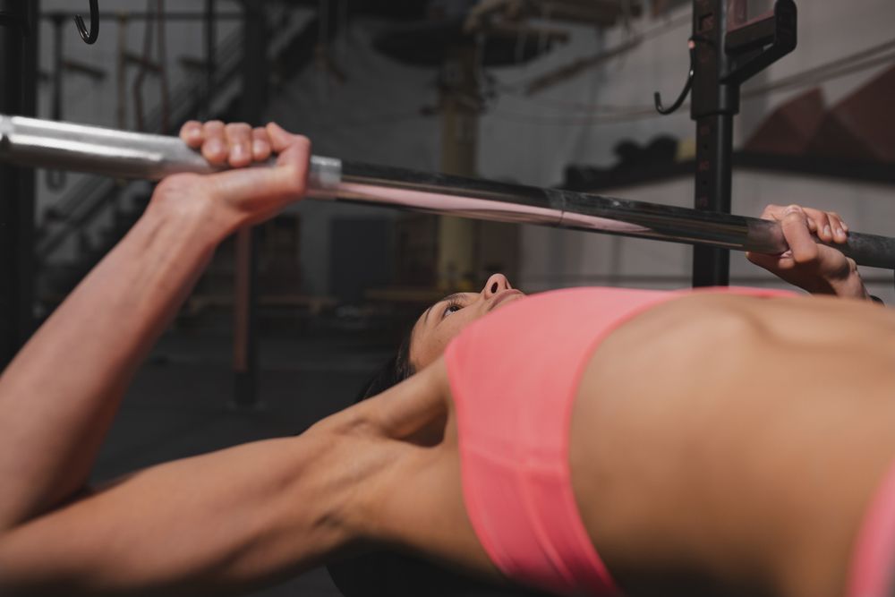 Athletic woman training with barbells in gym