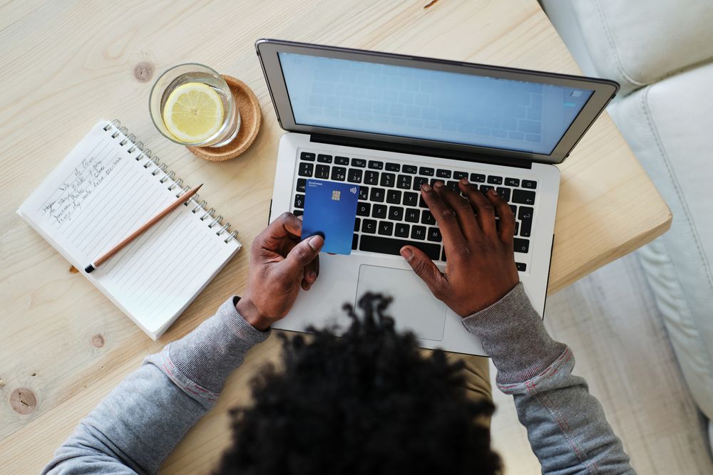 Crop Black buyer with credit card and laptop shopping online
